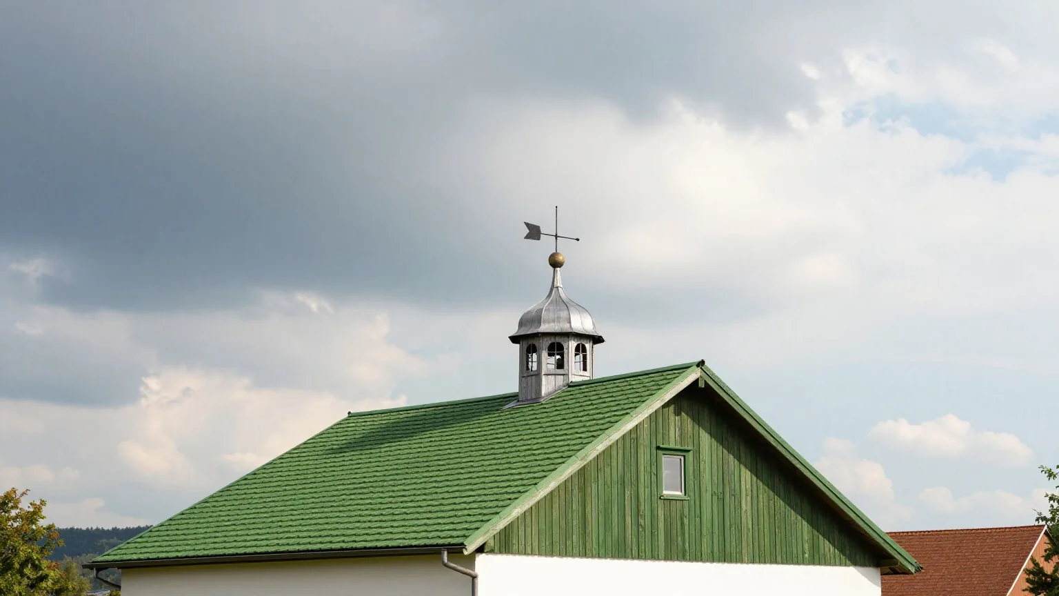 Eine Wetterfahne auf dem Dach einer alten Scheune vor einem Himmel, an dem Sturmwolken der Sonne weichen